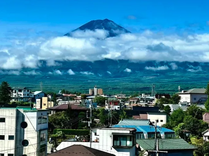 Mount Fuji rising above a layer of cloud and the rooftops of Fuji Kawaguchiko