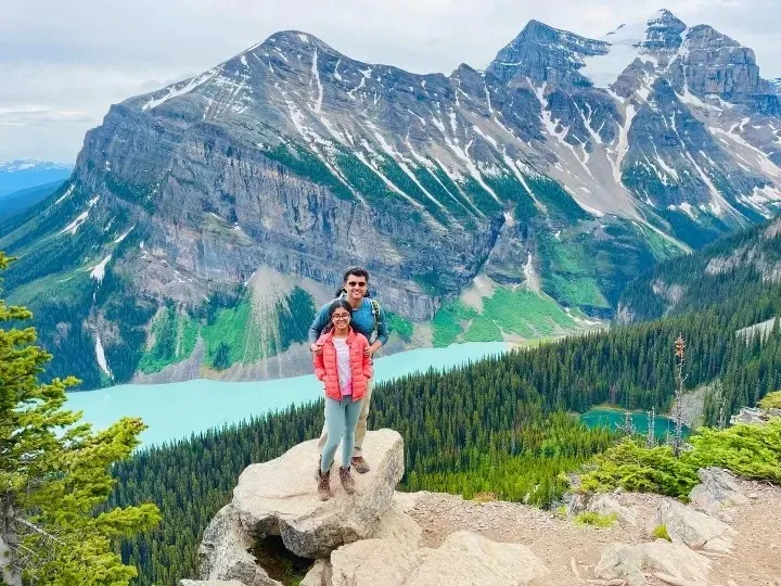 Ananya and her Dad standing on a boulder above turquoise Lake Louise