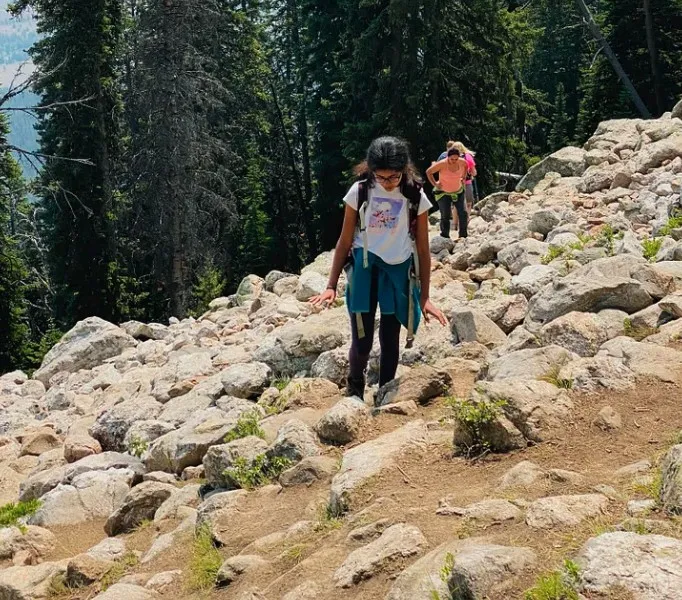 Ananya climbing up a boulder field, with other hikers behind her
