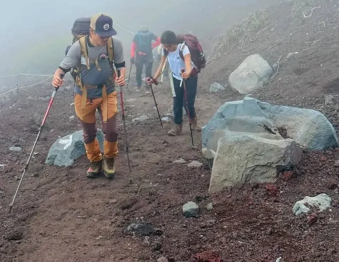 Ananya and her guide Masa climbing through thick fog on volcanic gravel