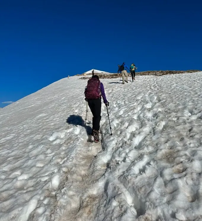 Ananya climbing an icy snow slope with the false summit ahead