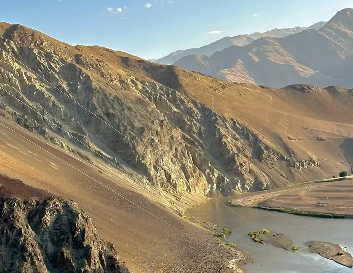 The river below a steep golden mountainside in Ladakh