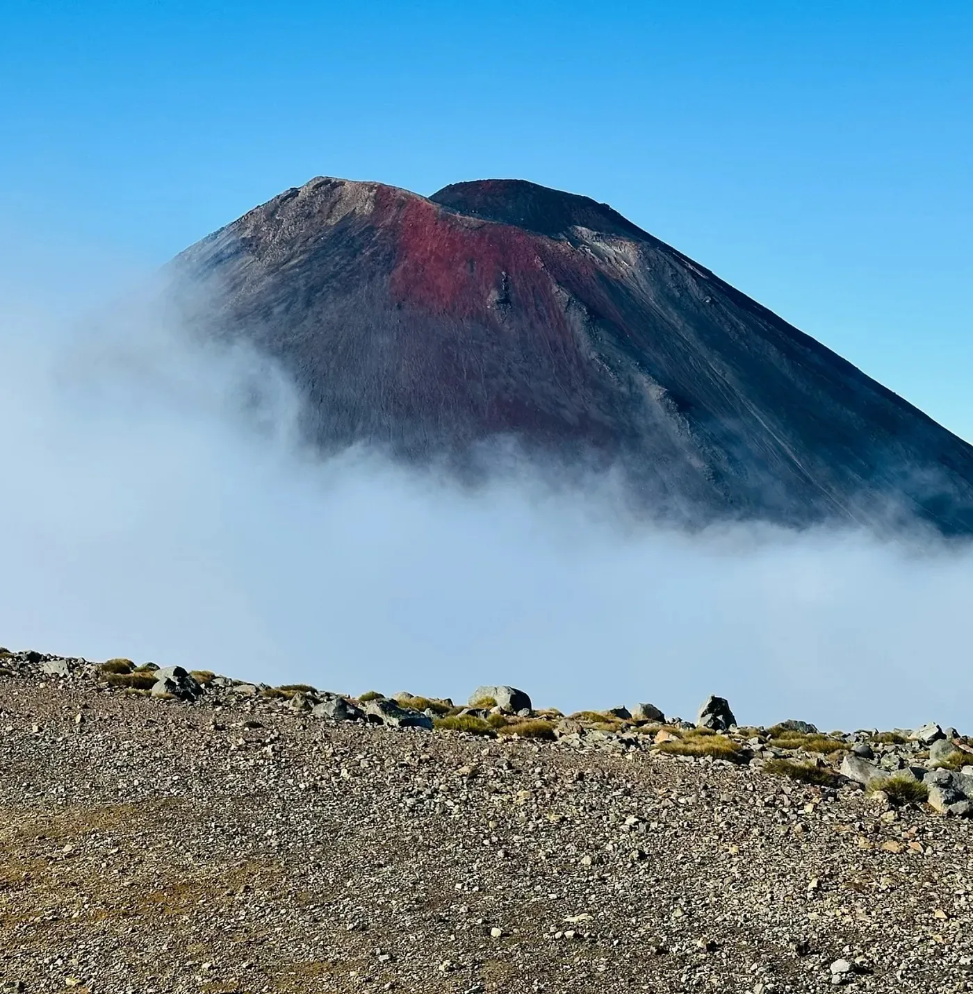 The red-streaked volcanic cone rising above the clouds
