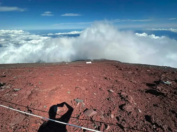 Red volcanic ground and a sea of cloud seen from the Mountain Hut